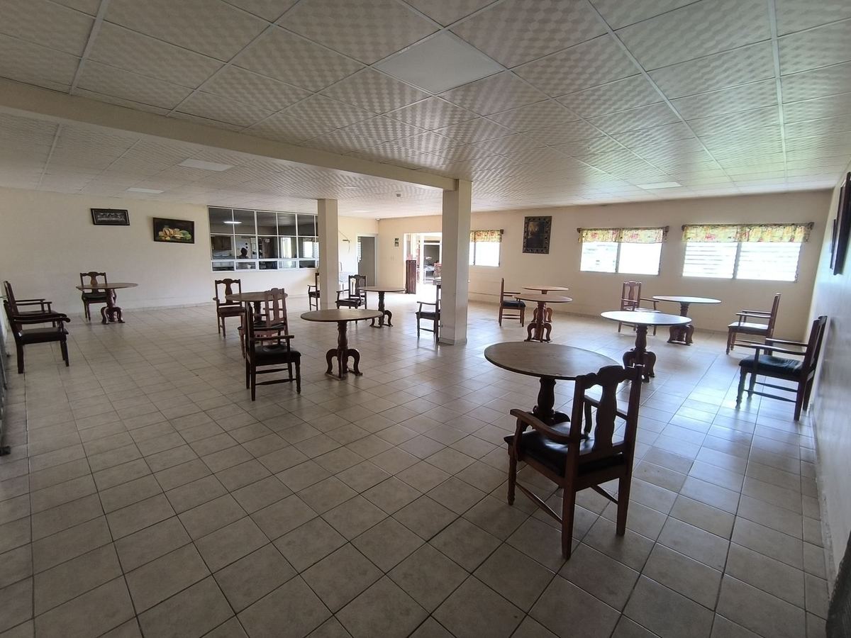 Comedor y sala común con mesas redondas de madera y ventanas con cortinas